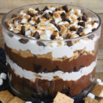 S'mores Trifle in a large trifle dish with graham crackers and marshmallows scattered in the foreground