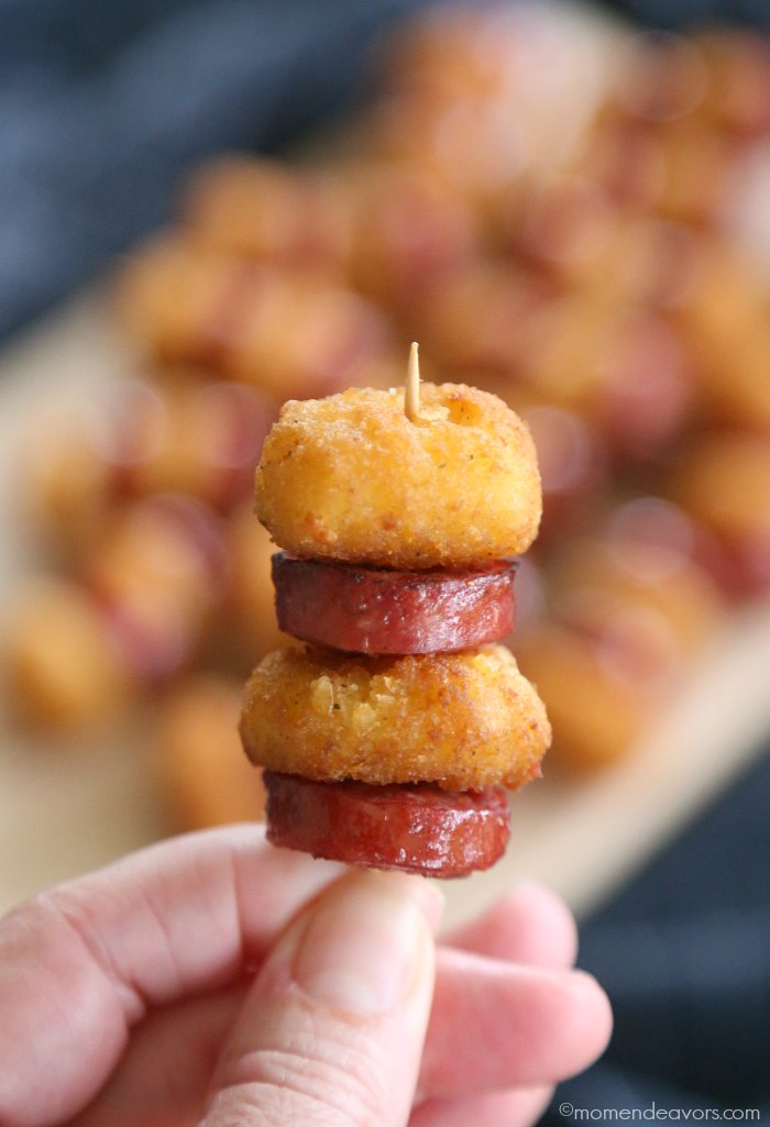 Hand holding a skewer with cheese curds and sausage bites